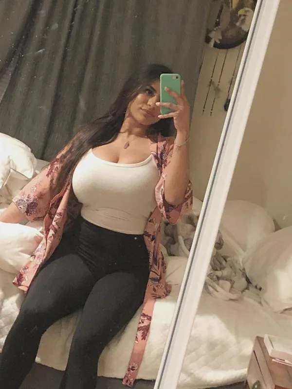 Femme prenant un selfie en miroir dans sa chambre, vêtue d'un haut blanc et d'un kimono floral.